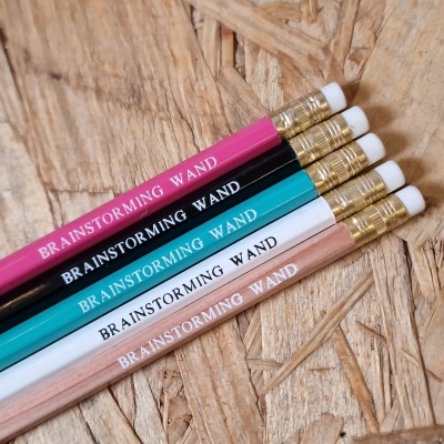 Cinco lápis coloridos com texto BRAINSTORMING WAND sobre superfície de madeira OSB
