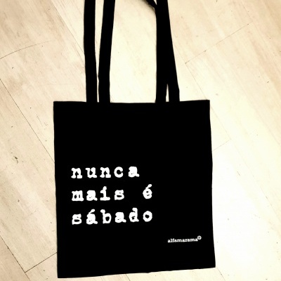Saco de pano preto com texto branco 'nunca mais é sábado'