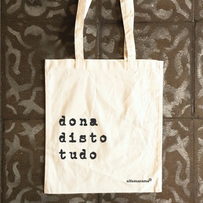 Saco de tecido branco com texto preto 'dona disto tudo'