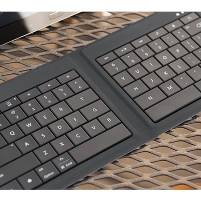 Teclado compacto dobrável preto sobre mesa metálica reticulada
