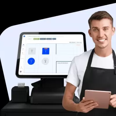 Homem com avental a usar tablet junto a terminal de ponto de venda com ecrã