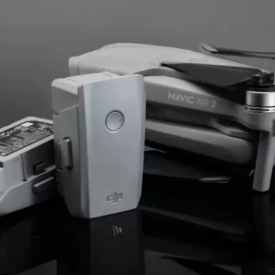 Dron DJI MAVIC AIR 2 cinzento dobrado com duas baterias ao lado.