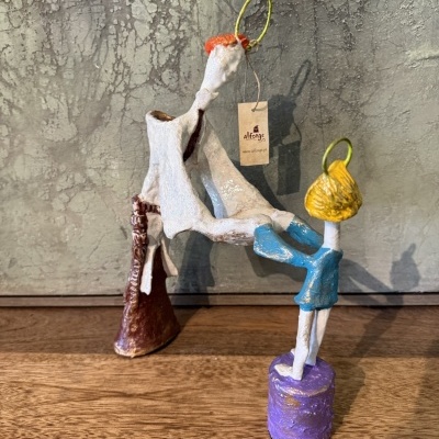 Escultura cerâmica abstrata colorida em fundo cinza sobre madeira