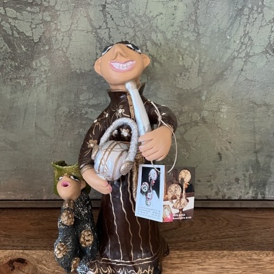 Estatueta decorativa de boneco sorridente em roupa castanha com gato preto ao lado