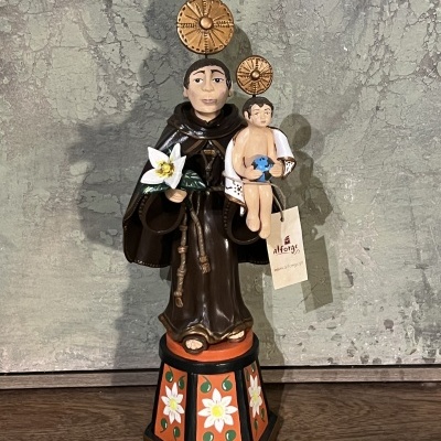 Estátua religiosa em madeira pintada com santo e criança em base decorativa colorida.