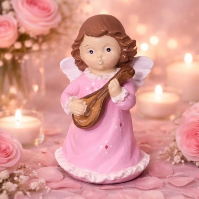 Estatueta de anjo a tocar instrumento com vestido rosa, flores e velas ao fundo