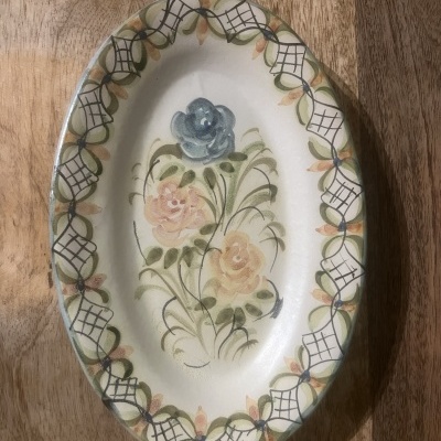 Travessa oval de cerâmica decorada com flores e padrão geométrico na borda