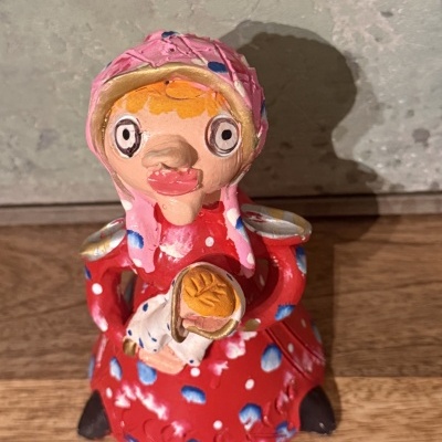 Figurinha cerâmica mulher com vestido vermelho e lenço cor-de-rosa segurando pão