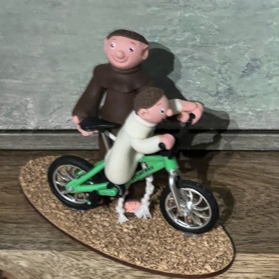 Estatueta de duas figuras com bicicleta verde sobre base oval