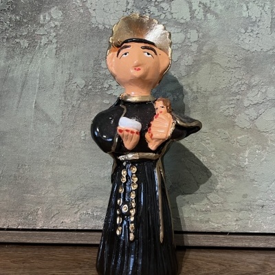 Figurine de padre em cerâmica com bebé e objeto nas mãos