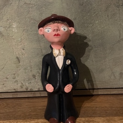 Figura decorativa masculina em cerâmica com fato preto e chapéu castanho