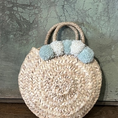 Bolsa redonda de palha com pompons azuis e brancos