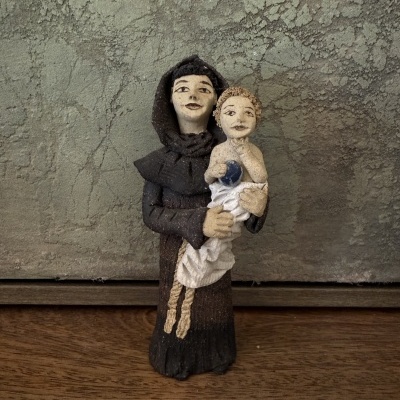 Estátua de homem segurando bebé em pano branco e azul com fundo parede cinzenta