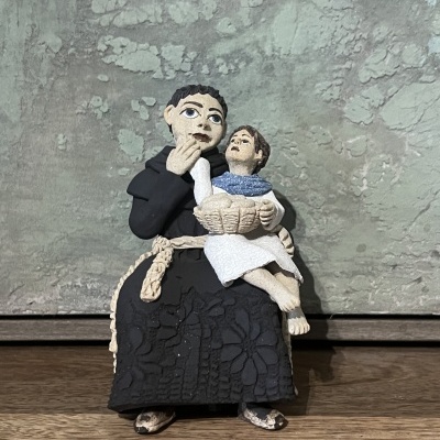 Estátua cerâmica de homem adulto com criança na sai.