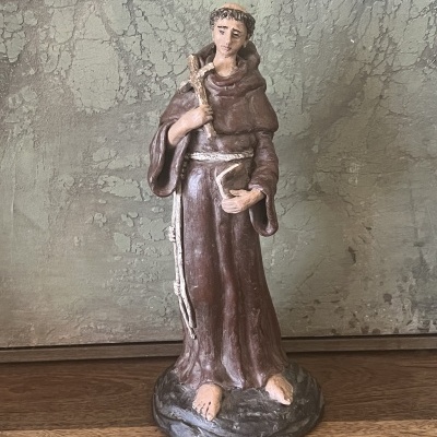 Estatueta de São Francisco em túnica castanha segurando cajado e livro