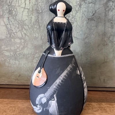 Figura decorativa de mulher com vestido preto e alaúde em cerâmica.