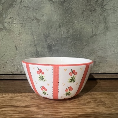 Tigela branca de cerâmica com flores vermelhas, borda laranja, sobre madeira