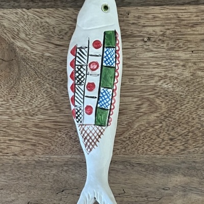 Peixe decorativo em cerâmica com padrão colorido sobre madeira