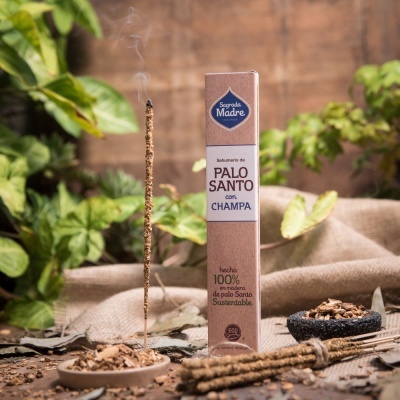 Embalagem de Incenso de Palo Santo com Champa da Sagrada Madre com incenso aceso e pedaços de madeira num cenário natural.