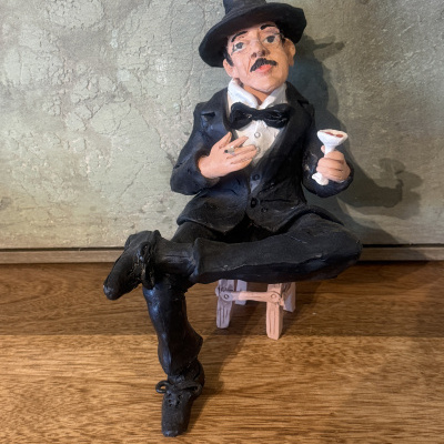 Estatueta de homem elegante a sentar-se com copo e cigarro.