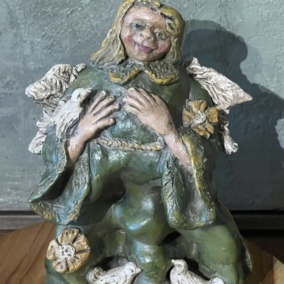 Estátua de anjo em cerâmica colorida com pássaros num fundo cinza