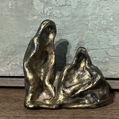 Escultura abstrata em metal dourado com duas figuras humanas estilizadas