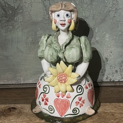 Figura decorativa em cerâmica de mulher com vestido verde e flor amarela