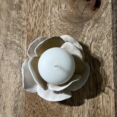 Vela branca em suporte de flor cerâmica sobre madeira