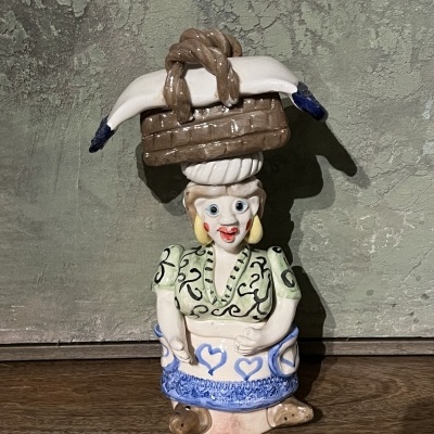 Figura decorativa em cerâmica de mulher com cesto na cabeça e saia azul e branca