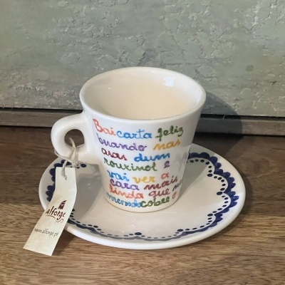 Chávena de cerâmica branca com texto multicolorido e pires branco com padrão azul escuro