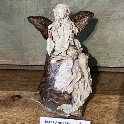 Escultura de anjo bege e castanho com base de madeira e etiqueta ESTER ANDRADE