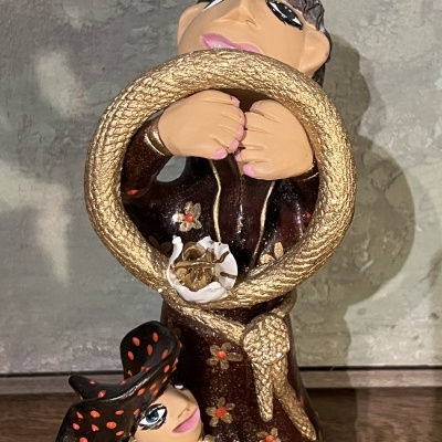 Estatueta em cerâmica de duas figuras femininas com roupas castanho e dourado.