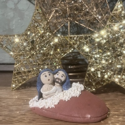 Figura decorativa da Sagrada Família num sapatinho vermelho, com estrelas douradas ao fundo