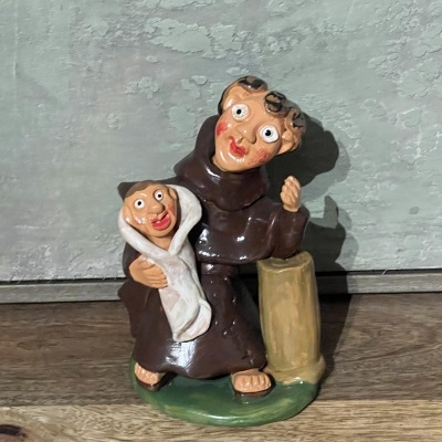 Estátua de cerâmica de duas figuras com roupas marrons sobre base verde e bege