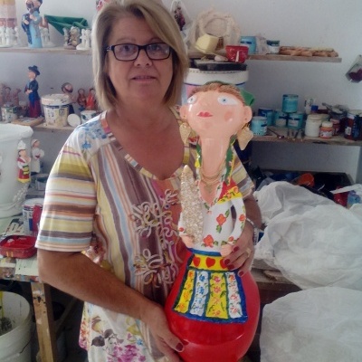 Mulher segura escultura colorida com rosto grande em estúdio de arte