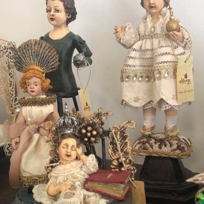 Quatro bonecos decorativos cerâmicos com roupas em tons claros e escuros e coroas prateadas ou douradas.