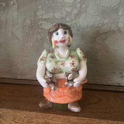 Figura decorativa de mulher em cerâmica com vestido verde e saia laranja