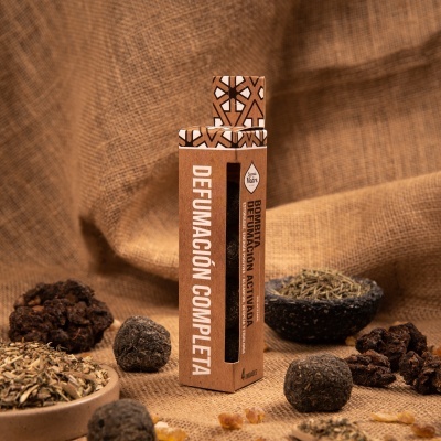 Embalagem castanha de defumação com texto e várias ervas e bolas secas ao redor sobre fundo de tecido.