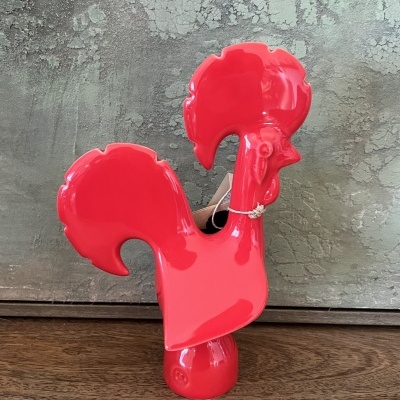 Estatueta decorativa vermelha em forma de galo sobre superfície de madeira