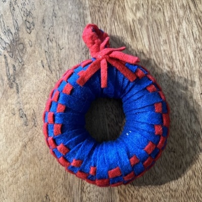 Brinquedo redondo azul e vermelho em tecido sobre madeira