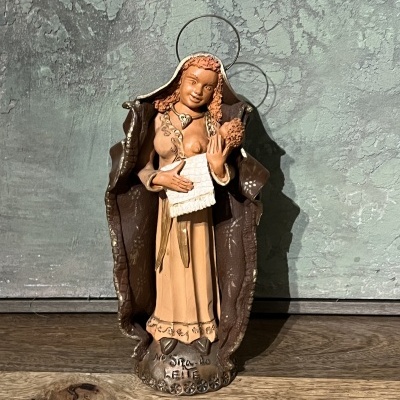 Escultura decorativa de figura feminina com capa castanha e pergaminho