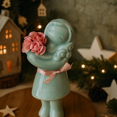 Figura decorativa em cerâmica verde água segurando flores cor-de-rosa