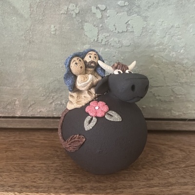 Escultura cerâmica de casal a montar touro castanho com flor decorativa