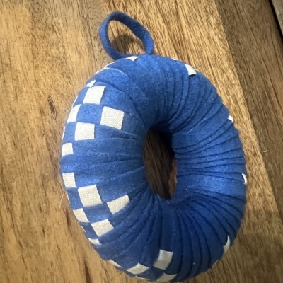 Almofada redonda azul com padrão branco e alça sobre madeira