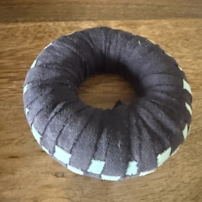 Dispositivo circular com tecido preto e pontos azuis claros sobre madeira.