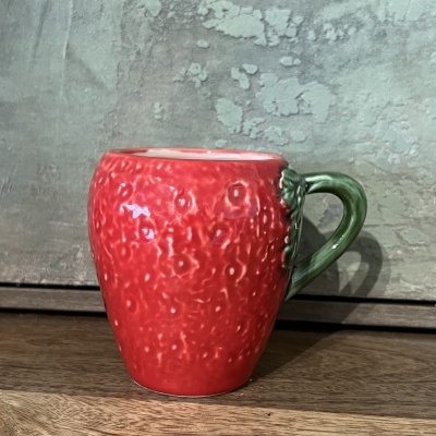 Caneca cerâmica vermelha com textura de morango e pega verde