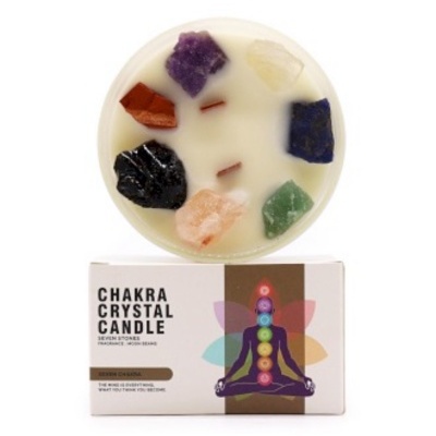 Vela branca com pedras coloridas sobre caixa com ilustração de chakras e texto CHAKRA CRYSTAL CANDLE