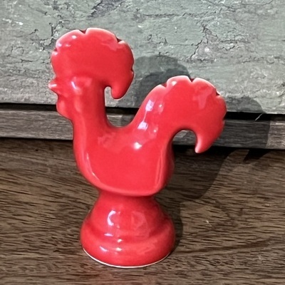 Figura decorativa vermelha em forma de galo em cerâmica sobre madeira