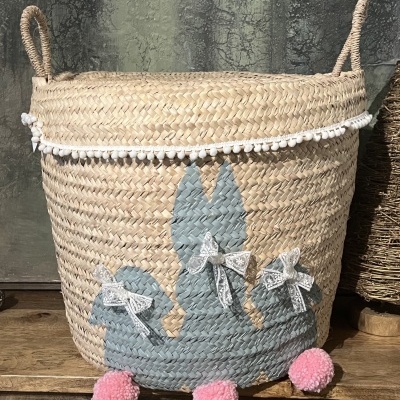 Cesto de palha decorativo com cacto cinzento, pompons rosas e renda branca