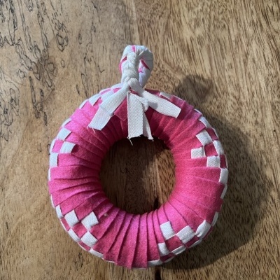 anel trançado cor-de-rosa e branco de tecido sobre superfície de madeira